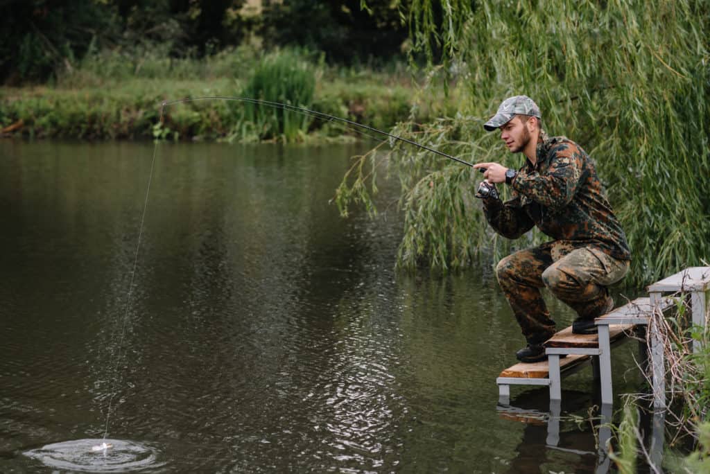 Fishing in river.A fisherman with a fishing rod on the river bank. Man fisherman catches a fish pike.Fishing, spinning reel, fish, Breg rivers. - The concept of a rural getaway.