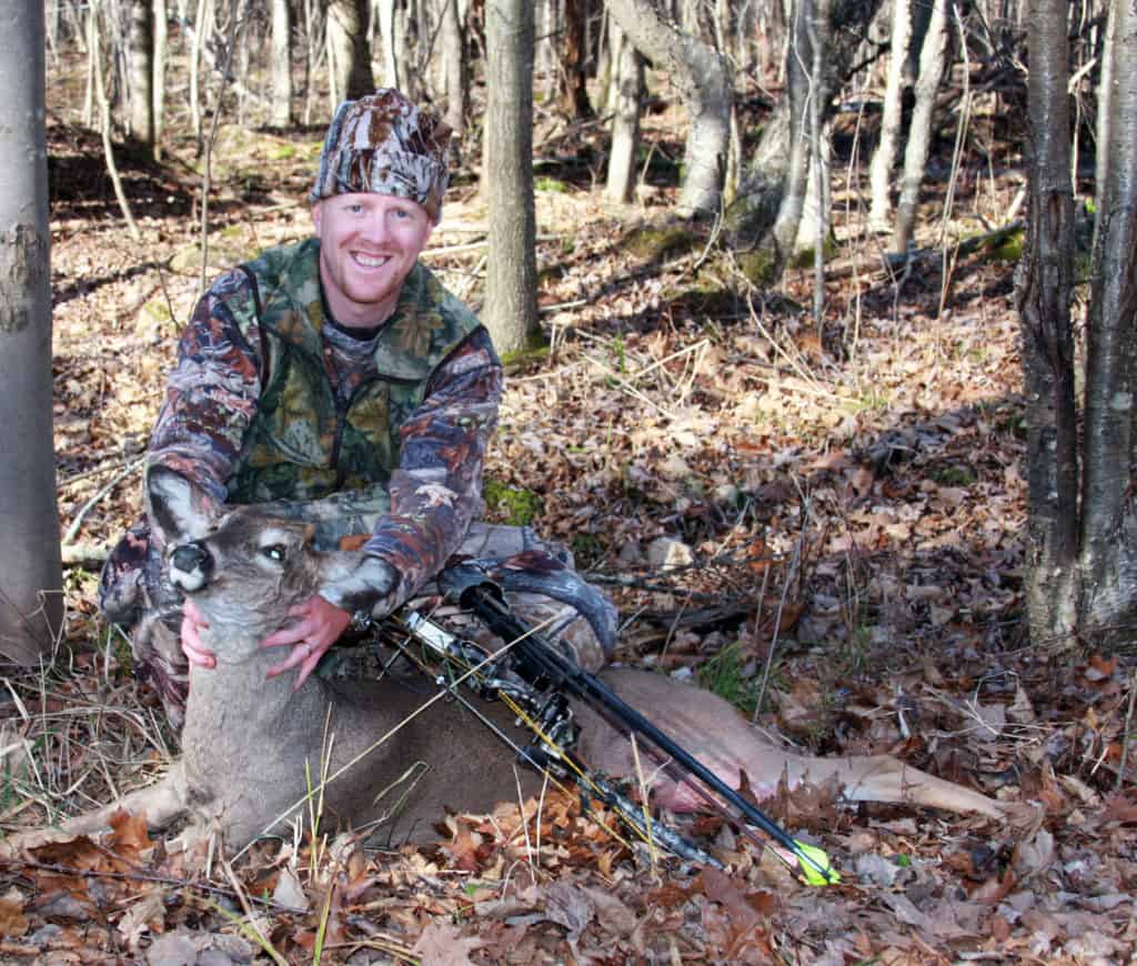 bow hunter with a whitetail doe dressed in camouflage