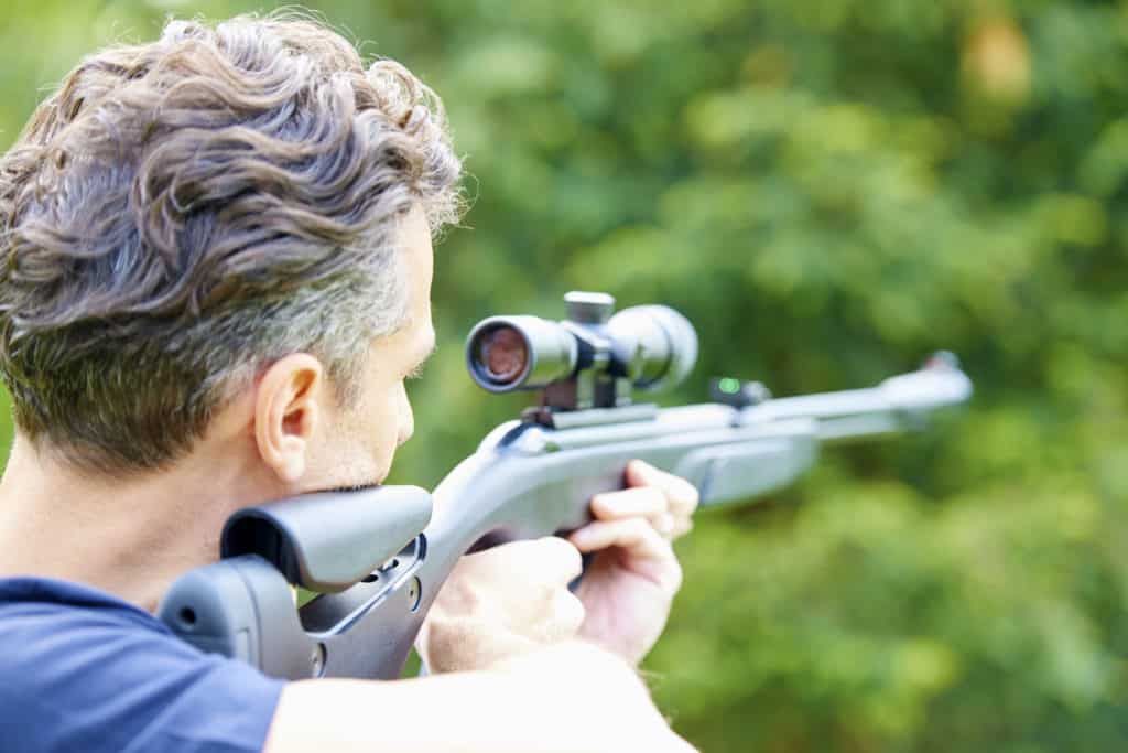 Rear view shot of a man with airgun practicing at the shooting range.
