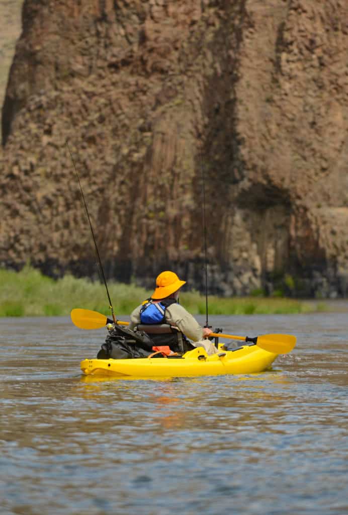 man Fishing and Kayaking in a yellow kayak with a yellow hat on John Day River in Central Oregon