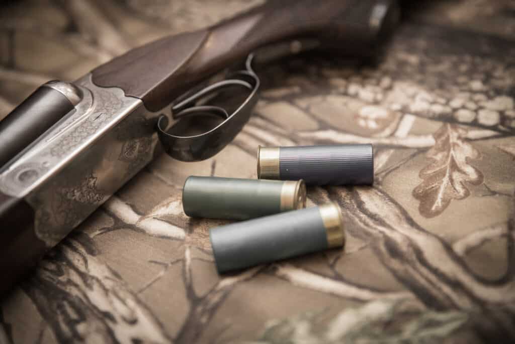 A wooden retro shotgun with shotgun shells