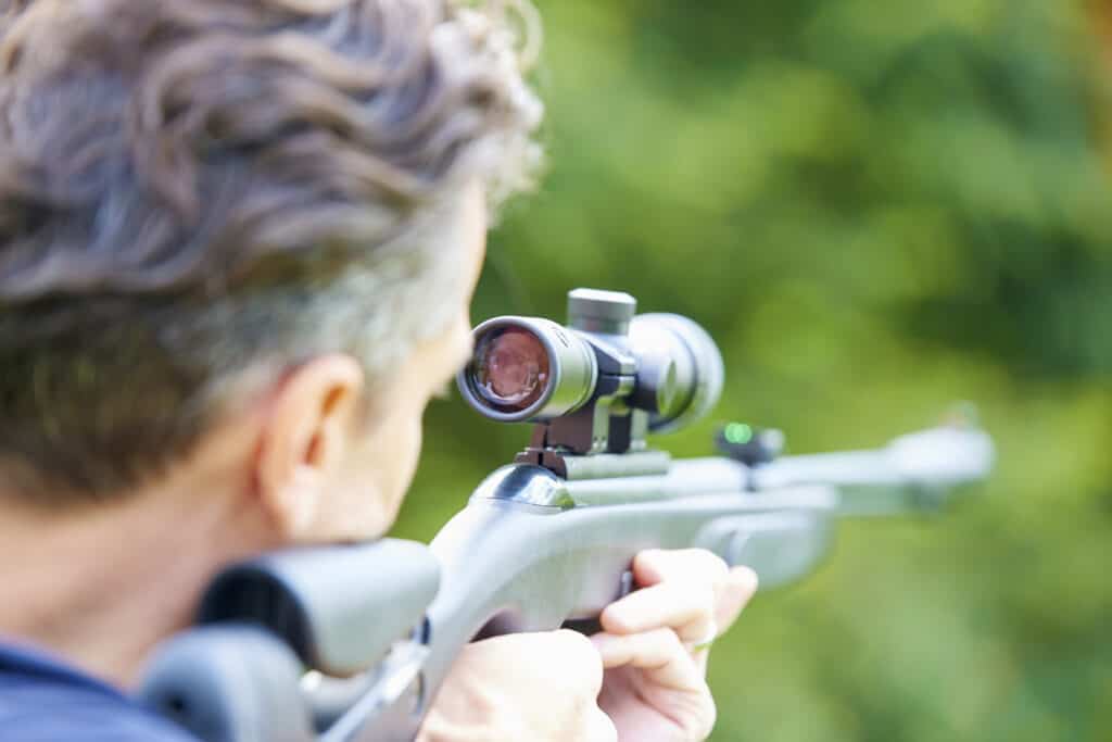 Rear view shot of a man with airgun practicing at the shooting range.