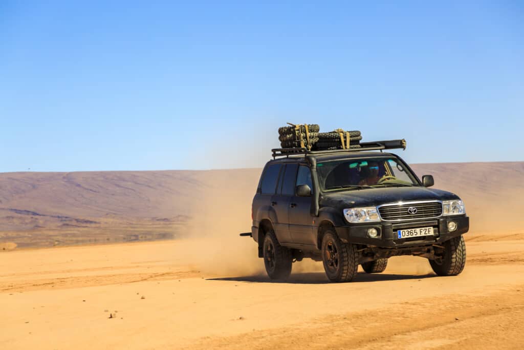 Ait Saoun, Morocco - February 22, 2016: Man driving toyota land cruiser in Ait Saoun desert of Morocco on a bright sunny day.